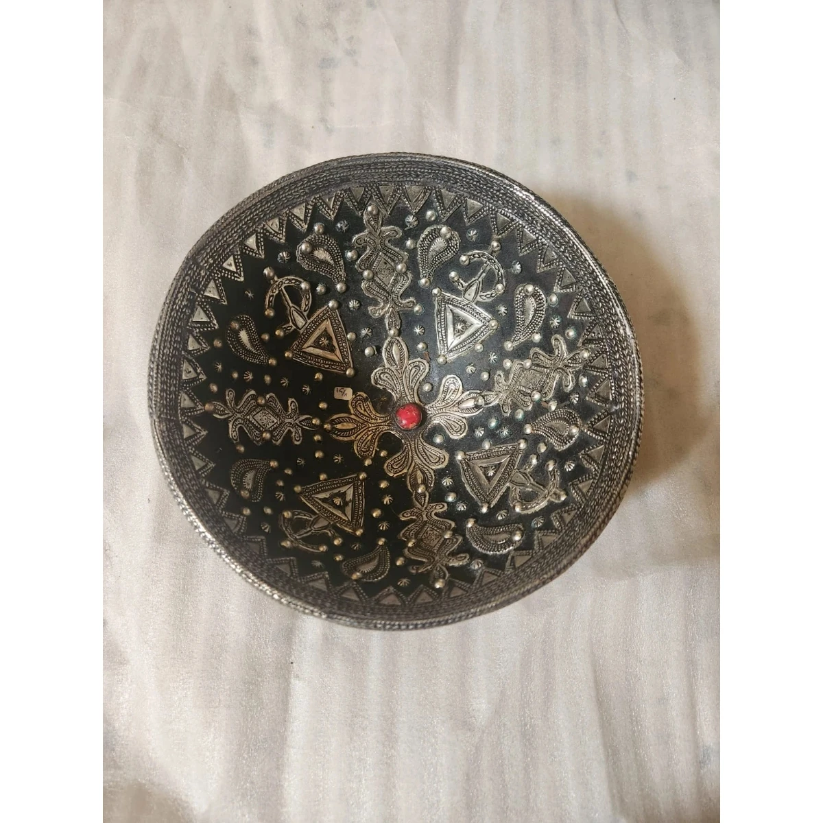 A ceramic and metal plate, featuring an intricate geometric design.